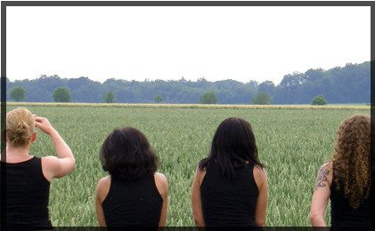 Four women sitting next to rice field