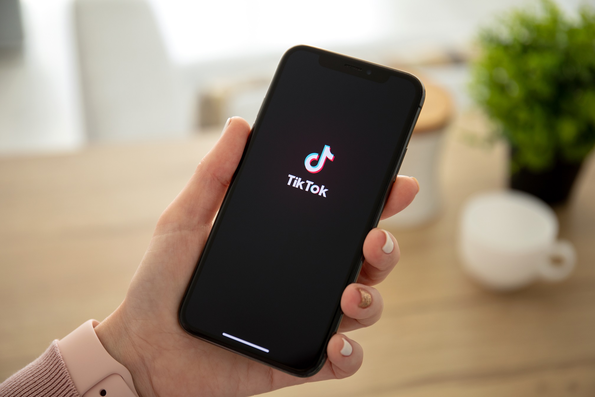 oman holding iPhone X with streaming service media and video TikTok on the screen. iPhone ten was created and developed by the Apple inc.